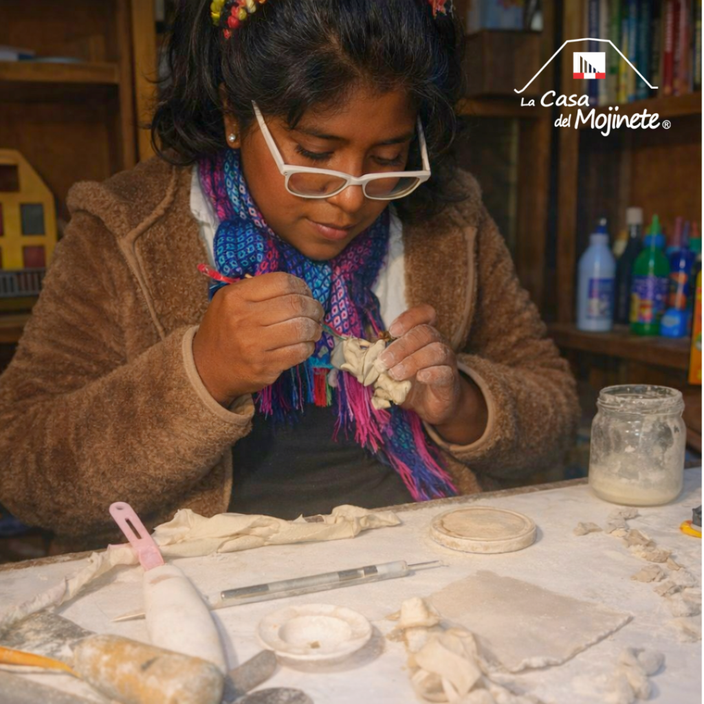 Artesana modelando una figura de pasta de yeso con herramientas manuales en un taller de trabajo.