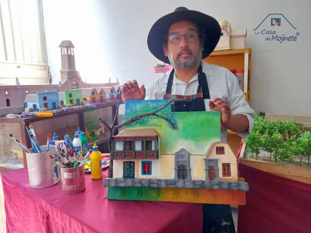 Artesano Sergio Ilich mostrando maqueta de arquitectura tacneña estilo casa de mojinete en su taller con materiales de arte